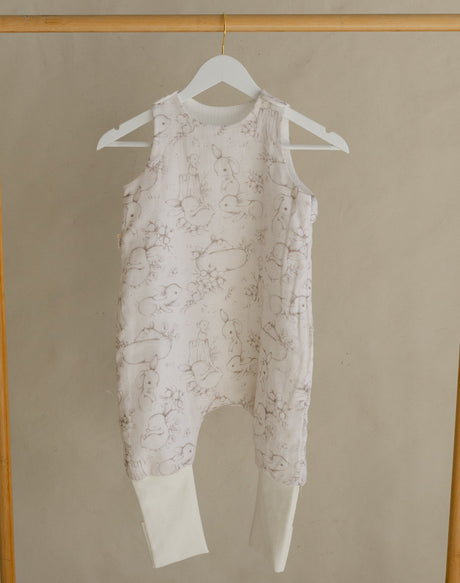 Gold clothing rack with a white baby romper on a beige background