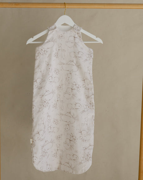 Light-colored dress with floral pattern hanging on a wooden rack against a beige wall.