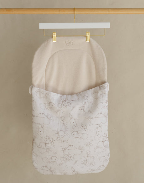 Wooden clothing rack with two hanging items against a beige wall.
