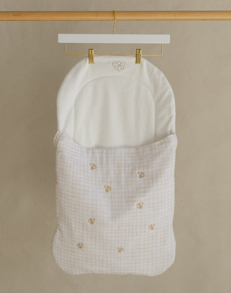 Wooden garment rack with a white baby bag on a beige background