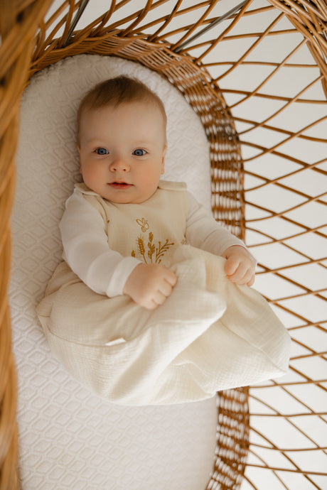 Baby lying in a wicker crib with a white blanket