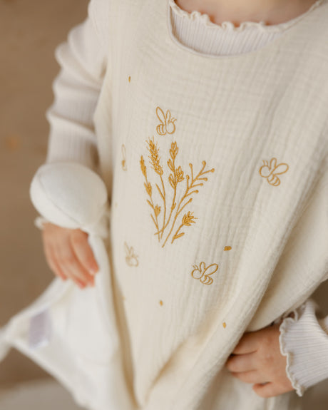 Close-up of a child wearing a cream-colored sweater with floral embroidery.