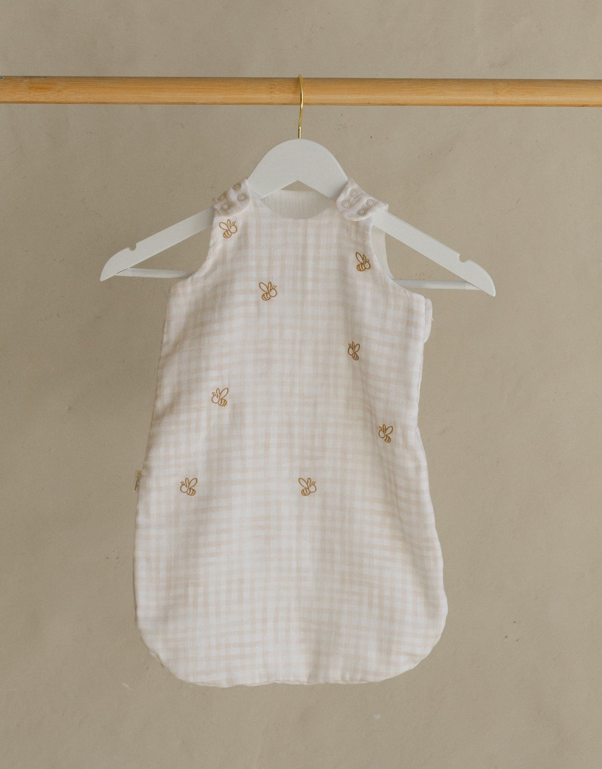 Wooden clothing rack with a white dress on a beige background