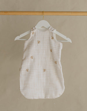 Wooden clothing rack with a white dress on a beige background