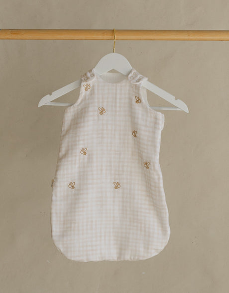 Wooden clothing rack with a white dress on a beige background