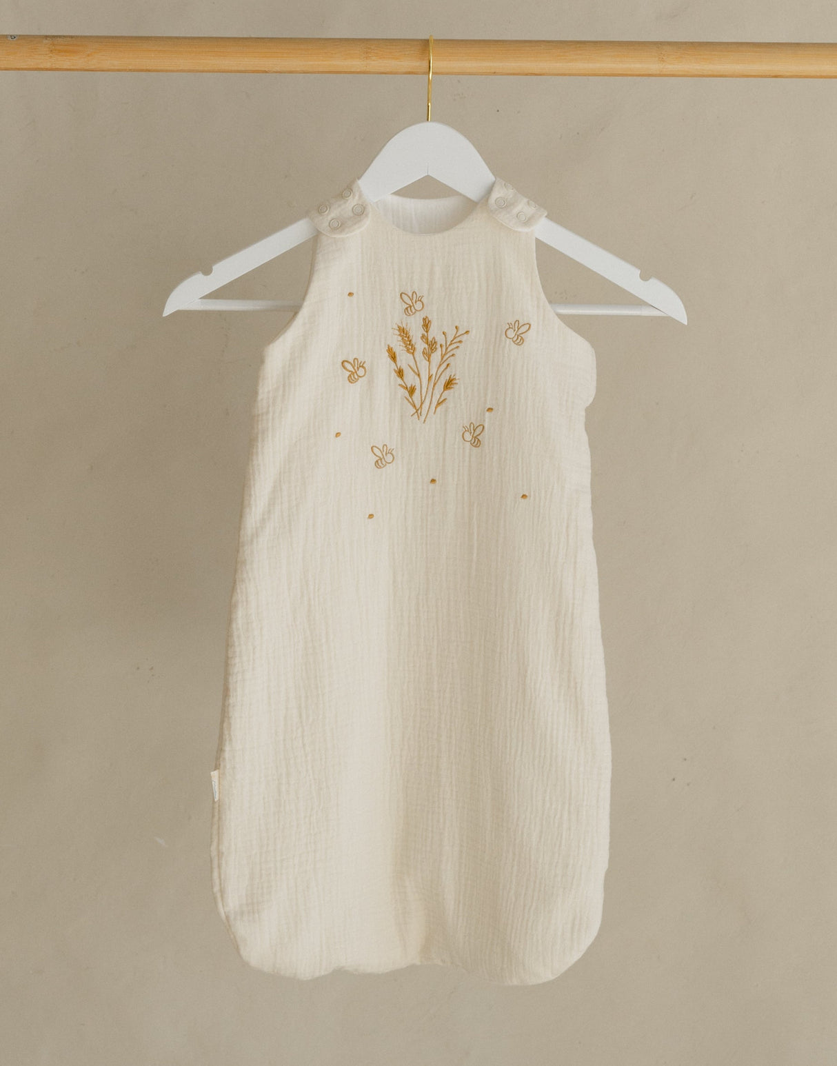 Wooden clothing rack with a white dress on a beige background