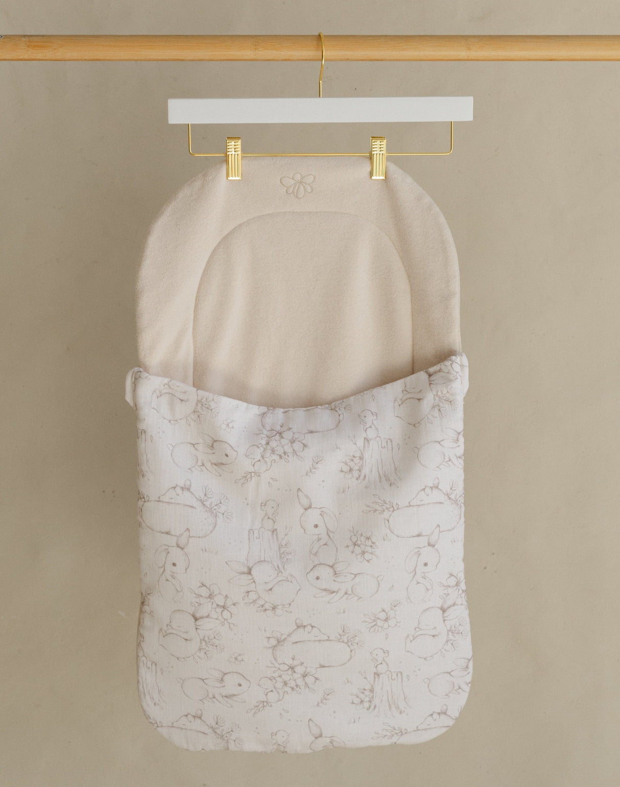 Wooden clothing rack with two hanging items against a beige wall.