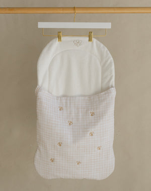 Wooden garment rack with a white baby bag on a beige background