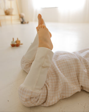 Person lying on a bed with feet up, wearing light-colored pants and socks.